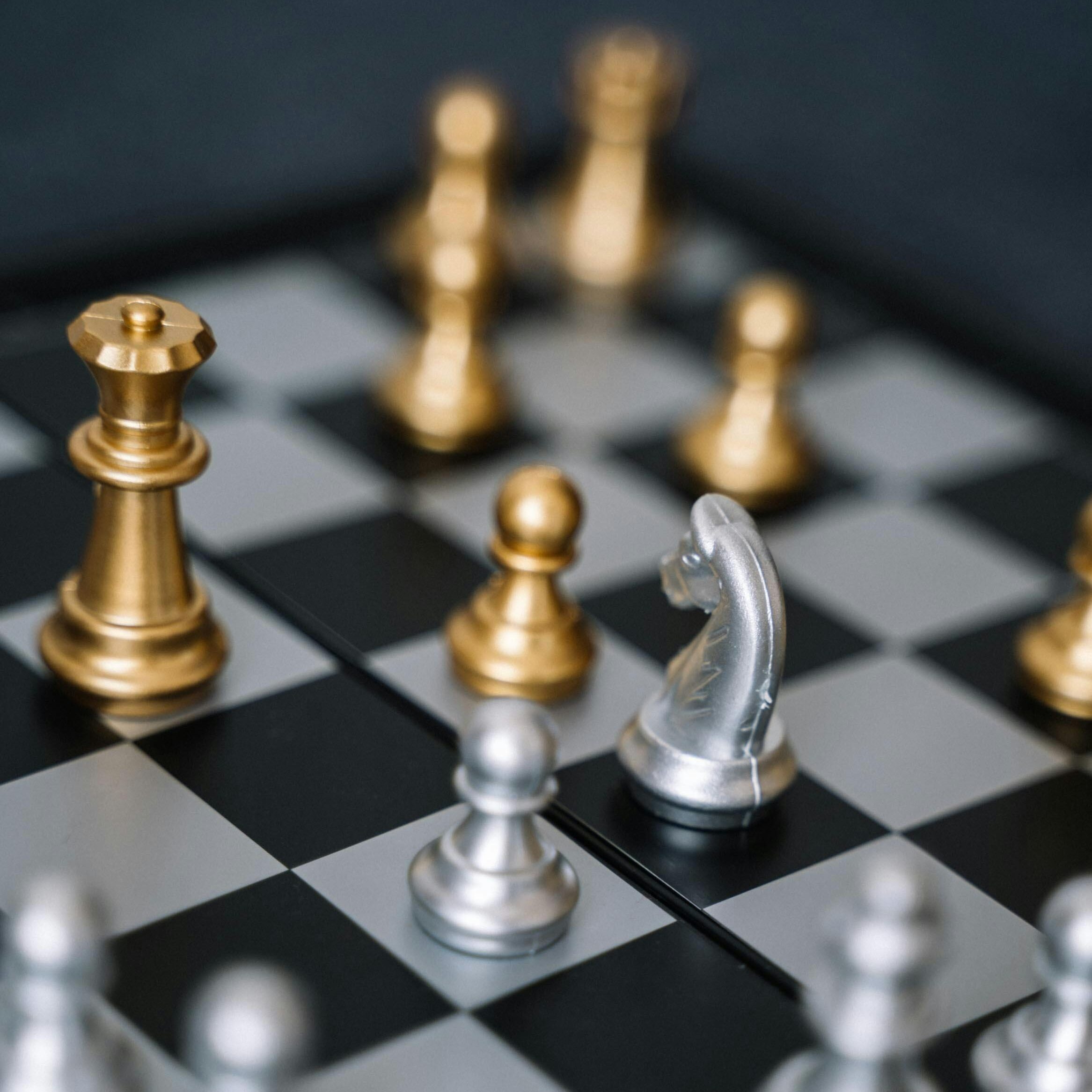 services-01 Macro shot of a chessboard featuring gold and silver pieces in strategic play.